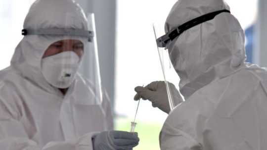 Zdravotníci v ochranných oblekoch testujú na koronavírus.