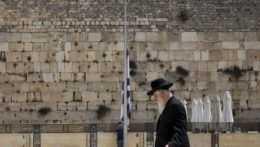 Izraelská vlajka visí na pol žrde počas štátneho smútku na pamiatku najmenej 45 obetí tlačenice, ku ktorej došlo počas náboženskej púte na horu Meron, pri Múre nárekov v Jeruzaleme 2. mája 2021.