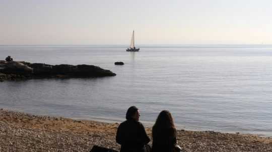 Na snímke ľudia sedia pri mori v Chorvátsku.
