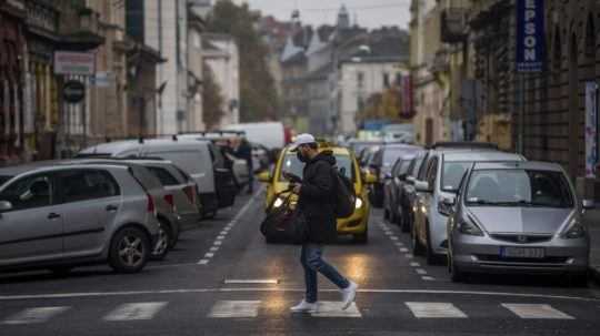 Muž s ochranným rúškom prechádza cez cestu v Budapešti