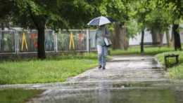 žena kráča s dáždnikom v bratislavskej mestskej časti Ružinov.