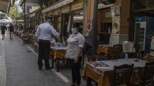 Čašníčka s ochranným rúškom čaká na zákaznikov na terase reštaurácie v Aténach v pondelok 3. mája 2021.
