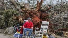 Steven West oddychuje pred veľkým stromom, ktorý spadol po vyčíňaní tornáda v meste Newman v americkom štáte Georgia 26. marca 2021.
