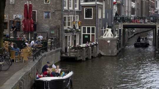 Ľudia na terasách podnikov v Amsterdame.