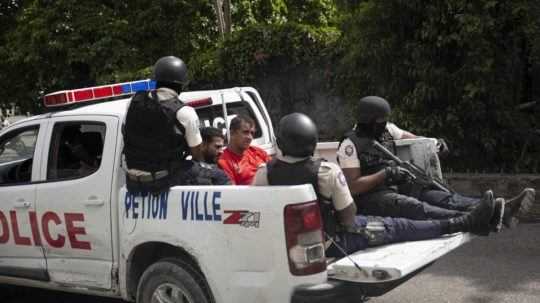 Haitské policajné auto so zadržanými mužmi.