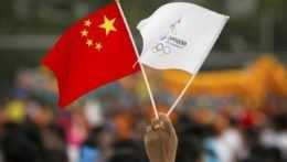 Žena drží čínsku a olympijskú zástavu Peking 2022