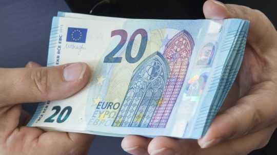 Človek drží v rukách dvadsaťeurové bankovky.