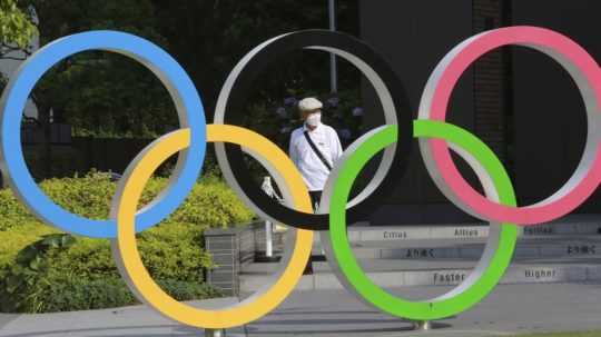 Muž kráča okolo olympijských kruhov v Tokiu.