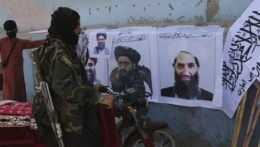 Bojovník Talibanu sa pozerá na plagáty lídrov hnutia Taliban na stene v Kábule.