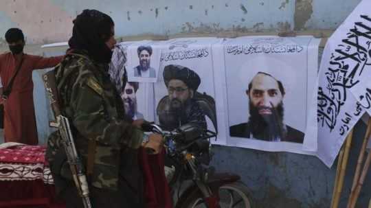 Bojovník Talibanu sa pozerá na plagáty lídrov hnutia Taliban na stene v Kábule.