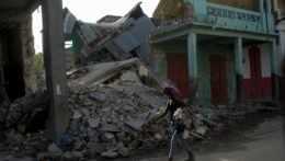 Žena kráča okolo trosiek domu v meste Jeremie na Haiti po zemetrasení.