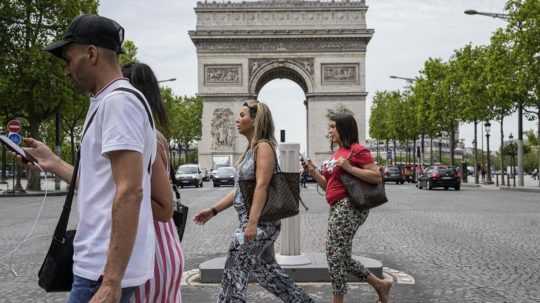 Ľudia kráčajú okolo Víťazného oblúka na Elyzejských poliach v Paríži.