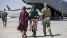 Americká vojačka kráča s afganskou rodinou do lietadla amerických vzdušných síl Boeing C-17 Globemaster III počas evakuácie na medzinárodnom letisku Hamída Karzaja v Kábule 25. augusta 2021.