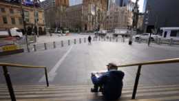 muž si číta noviny na schodoch v meste počas lockdownu v Melbourne