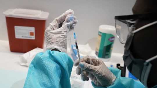 zdravotník naťahuje vakcínu do injekcie