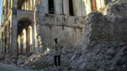 muž stojí pri troskách budovy po zemetrasení