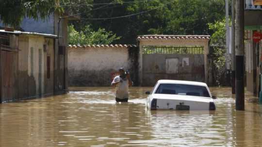 muž sa brodí zaplavenou ulicou vo Venezuele