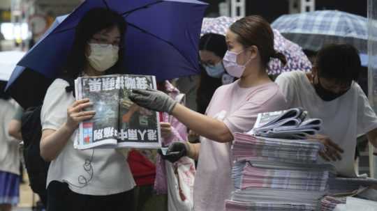 Ľudia si kupujú výtlačok novín hongkonského prodemokratického denníka Apple Daily v novinovom stánku na ulici v Hongkongu.