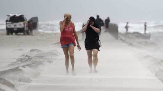 Ľudia si zakrývajú tváre počas búrky Nicholas v Texase.