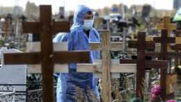 Hrobár v ochrannom odeve stojí počas pohrebu obete koronavírusu na cintoríne v Omsku