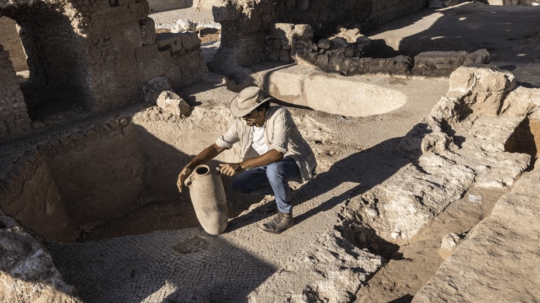 Archeológ drží starý džbán na víno.