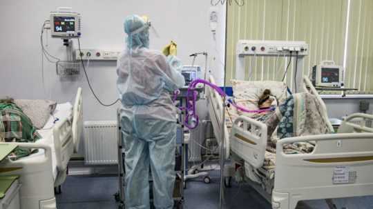 zdravotník v ochrannom obleku ošetrujúci pacienta s covidom v nemocnici