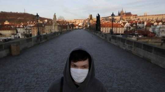 Na archívnej snímke zo 16. marca 2020 mladý muž s ochranným rúškom kráča po Karlovom moste v Prahe.