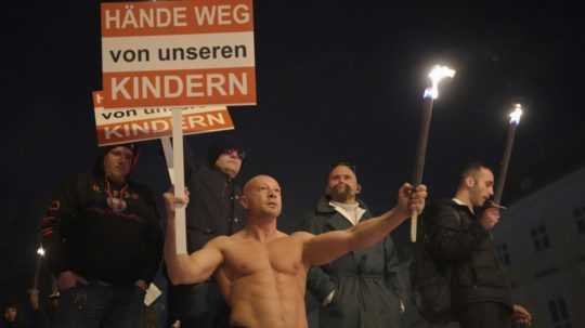 Účastník protestu vo Viedni drží tabuľu s nápisom "ruky preč od našich detí".