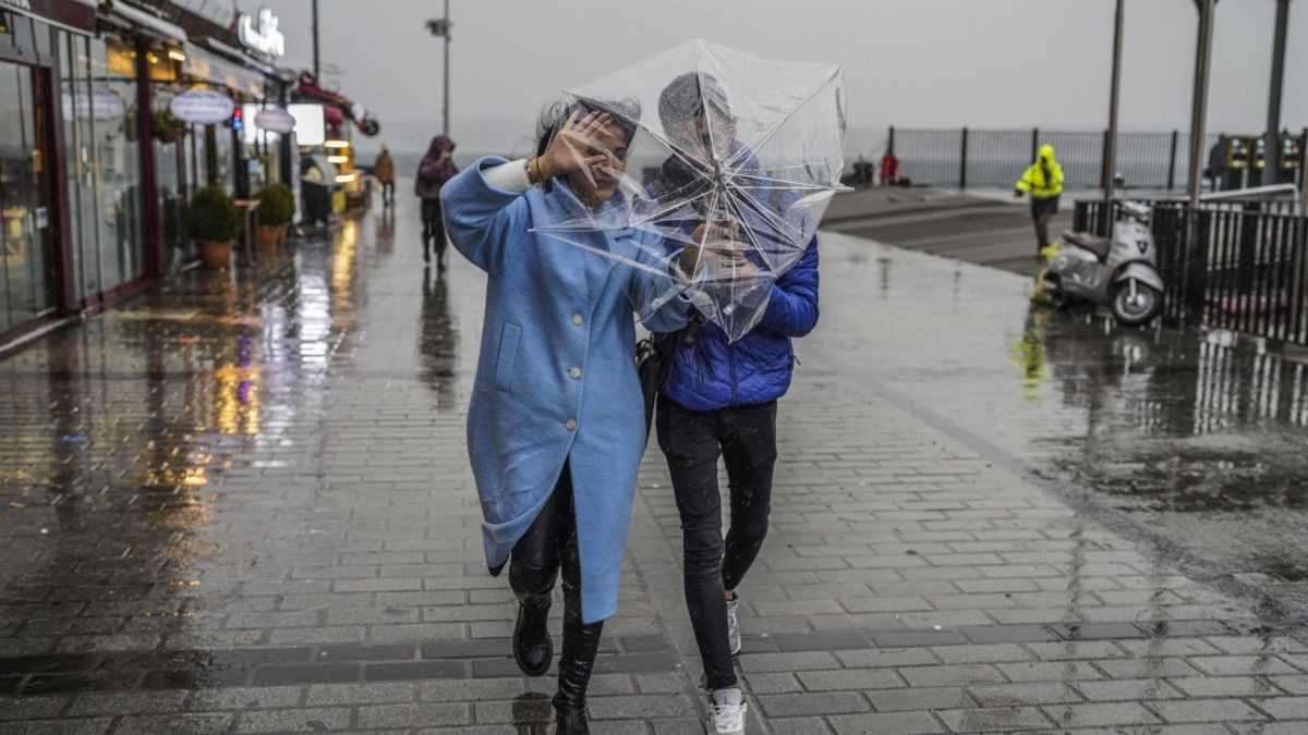 dvojica sa kryje dáždnikom pred dažďom a vetrom