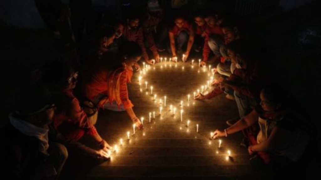 Ilustračná snímka - členovia indickej mimovládnej organizácie vytvárajú zo zapálených sviečok červenú stuhu, ktorá je symbolom boja proti AIDS.