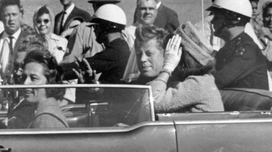 Na archívnej snímke z roku 1963 americký prezident John F. Kennedy máva zo svojho auta zhruba minútu pred svojou vraždou v Dallase.