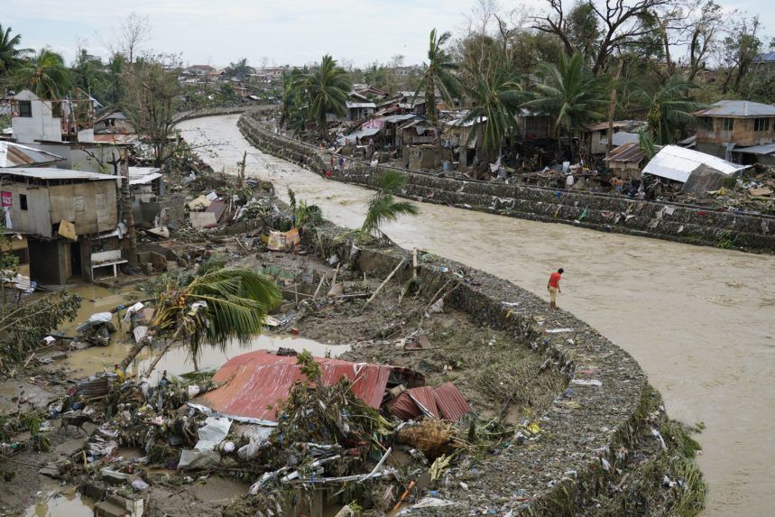 Muž pri rozvodnenej rieke a zničených domoch.