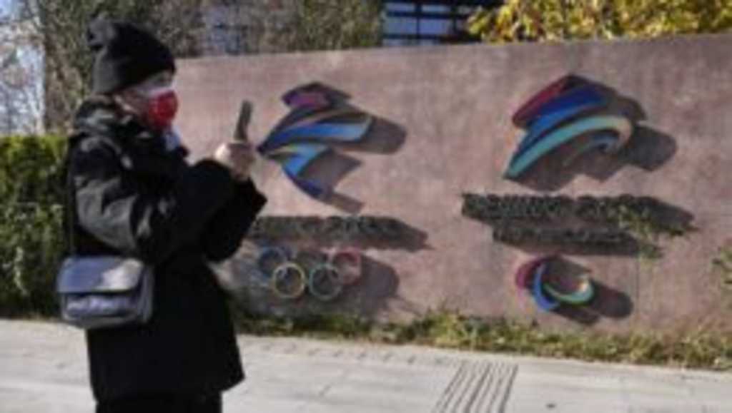 Návštevníčka kráča okolo log pre zimné olympijské hry a paralympijské hry 2022 v Pekingu.