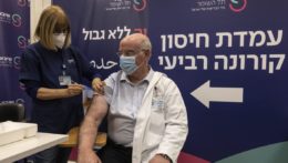 Zdravotná sestra podáva štvrtú dávku očkovania izraelskému profesorovi.