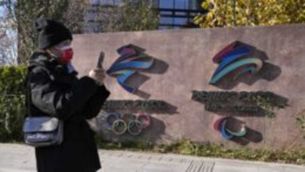 Návštevníčka kráča okolo log pre zimné olympijské hry a paralympijské hry 2022 v Pekingu.