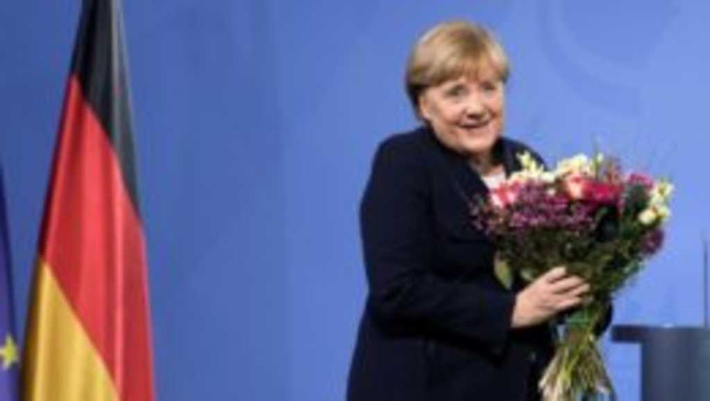 Bývalá nemecká kancelárka Angela Merkelová drží kyticu kvetov, ktorú dostala od novozvoleného nemeckého kancelára Olafa Scholza.