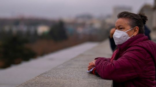 Žena má na tvári respirátor počas prechádzky v centre Madridu.