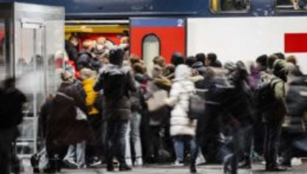 cestujúci s ochrannými rúškami nastupujú do vlaku v Zürichu