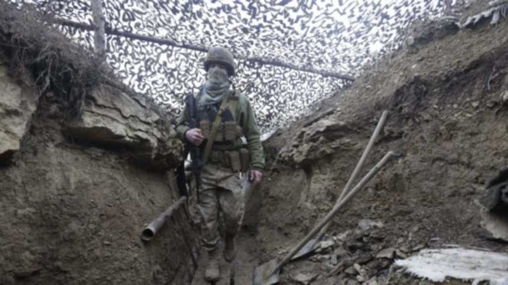 Ukrajinský vojak kráča pod maskovacou sieťou.