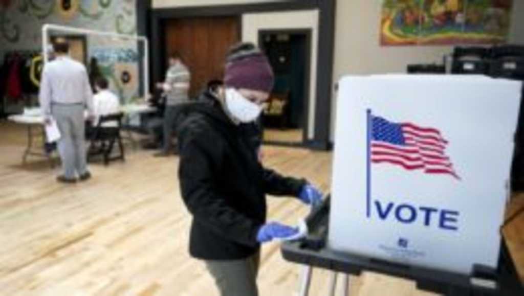 Na snímke volička dezinfikuje zariadenie na hlasovanie vo voľbách.
