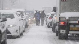 Ľudia kráčajú po ulici počas hustého sneženia v Aténach.