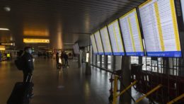 Na snímke cestujúci s ochranným rúškom pozerá na tabuľu odletov na medzinárodnom letisku Schipol neďaleko Amsterdamu.