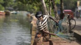Na snímke starší srílanský muž s kovbojským klobúkom a cigaretou nahadzuje rybársku sieť na vodnom kanáli v Colombe.