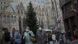 Ľudia s ochrannými rúškami kráčajú pred katedrálou Sv. Štefana na obchodnej ulici vo Viedni.