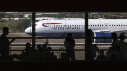 Cestujúci čakajú v odletovej hale, v pozadí je lietadlo britskej leteckej spoločnosti British Airways.