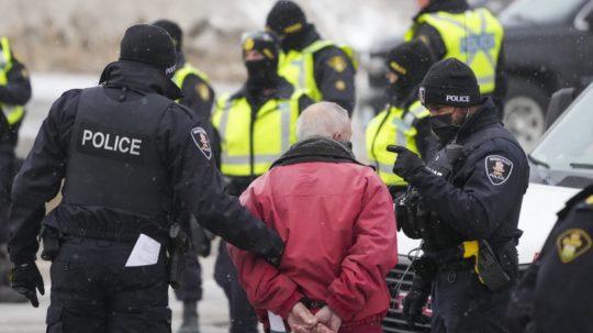 Policajti vedú v putách jedného z demonštrantov v Kanade.