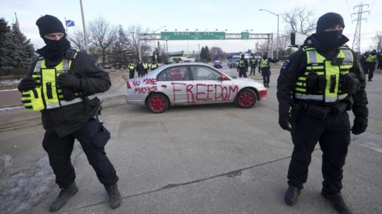 Policajti stoja počas demonštrácie proti pandemickým opatreniam na moste vedúcim do Spojených štátov v kanadskom meste Windsor.