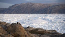 Vedci z Newyorskej univerzity sedia na vrchole skaly s výhľadom na ľadovec Helheim v Grónsku 16. augusta 2019. Topenie ľadovcov v Grónsku bolo v poslednom desaťročí omnoho rýchlejšie a tento rok v lete zaznamenali dve najväčšie topenia od roku 2012.