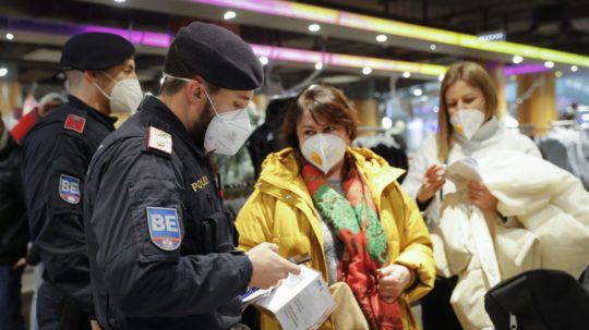Policajt kontroluje očkovací preukaz zákazníčky v nákupnom stredisku vo Viedni.