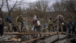 Ukrajinskí vojaci pomáhajú utekajúcej rodine pri prechode cez rieku Irpin na okraji Kyjeva.